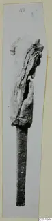 Heavily corroded bronze object from Lapithos Tomb 313 A, photographed upright on a mounted card.