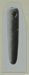 Elongated tapering object with a round perforation near one end, shown as a photograph mounted on a card