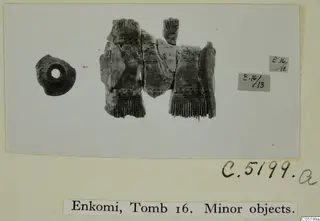 Fragmentary carved bone comb and a small perforated round object from Enkomi Tomb 16