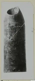 Find from Enkomi Tomb 3: a tall object with a rounded top and a dark opening, mottled surface