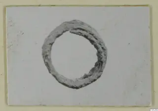Corroded metal ring lying on a white card, a find from Lapithos Tomb 409