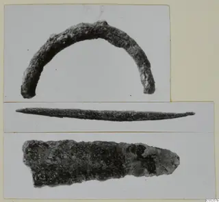 Three separate photographs of corroded metal finds: an arc-shaped bronze piece, a thin pointed rod, and a flat blade fragment.