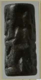 Cylinder seal from Enkomi, photographed upright on a grey card; the carved surface is blurred