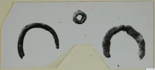 Three corroded metal objects from Enkomi, Tomb 3: two open curved arcs and a small ring with a central hole