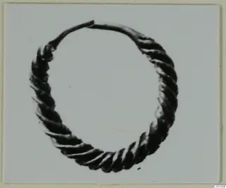 Twisted metal hoop ring from Enkomi, Tomb 3, shown on a grey card mount.