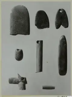 Several small stone objects from Kythrea, including perforated pendants and a tube-shaped piece, on a plain background.