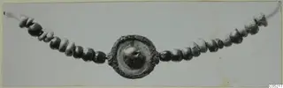 Necklace of small beads strung on a cord, with a round disc pendant with a raised central boss at the centre, on a pale card.