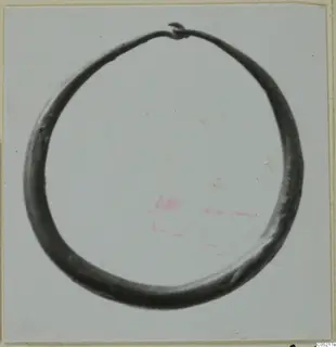 Single open ring of dark metal with a looped terminal at the top, shown on a pale card.