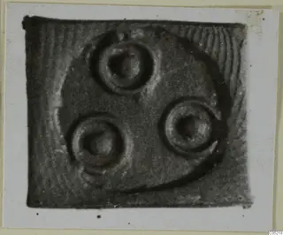Glyptic: close view of a small seal face with three circular motifs set within a curved rim