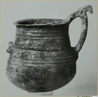 Pottery Black Slip Ware jug with a tall loop handle and a raised band of decoration around its body