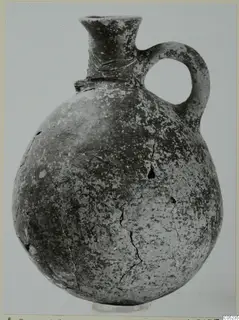 Pottery Black Slip Ware jug with a round body, flared neck and single loop handle