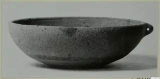 Pottery bowl-jar with a single pierced lug on one side of the rim, photographed on a plain background