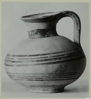 Pottery bowl-jar with a strap handle, a flaring rim and dark painted horizontal bands, shown against a plain background.