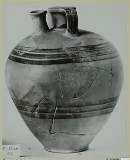 Pottery bowl-jar with a narrow spout, a strap handle and dark painted bands, its surface cracked where fragments have been joined