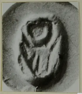 Close-up photograph of a carved seal or gem with a sunken design, shown on a pale ground.