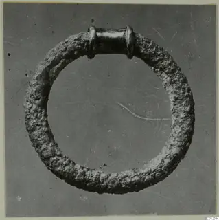 Ring with a thick, corroded hoop and a smooth tubular section with collars, from Ayios Iakovos