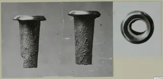 Two corroded metal tubular objects with flared rims, and an end view of a third ring-shaped object, photographed on a card