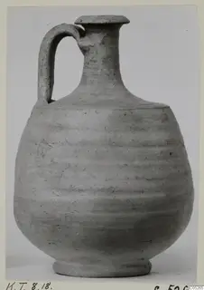 Grey pottery jug with a single strap handle and a flat, overhanging rim