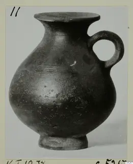 Dark-surfaced jug with a flared rim, globular body and single loop handle, from Kountoura Trachonia