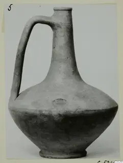 Jug with a single strap handle, a tall neck and a flared rim, shown in a photograph mounted on a card