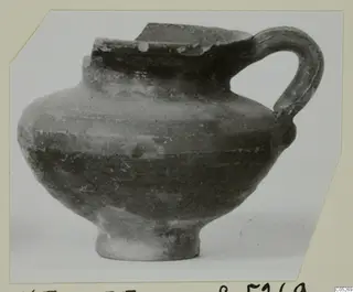 Cypro-Hell.I. jug with a strap handle and a broken rim, shown in side view.