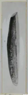Elongated dark stone object tapering at both ends, shown on a mounted card from Kythrea.