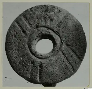 Disc-shaped find with a central hole and incised radial lines, from Lapithos, shown on a pale card mount