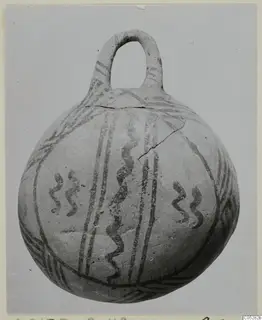 Round pottery vessel with a loop handle, decorated with dark painted bands and wavy lines, White Painted III-2