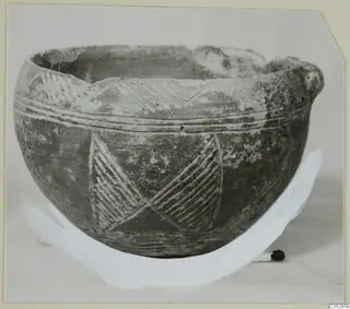 Pottery Red Polished III bowl with incised hatched and chevron decoration, photographed on a light surface