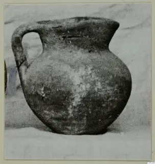Round-bodied jug with a single strap handle and a flaring rim, shown on a pale surface