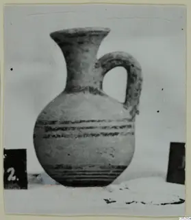 Pottery White Painted II, a jug with a flaring neck, a loop handle and dark painted bands on the body