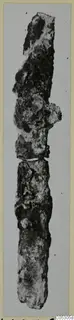Long, heavily corroded iron object, photographed upright against a pale grey background, Lapithos find