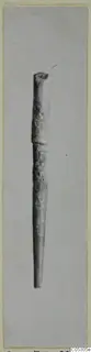 Bone pin, a long slender pin tapering to a point, photographed upright on a grey background