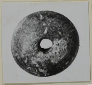 Disc-shaped object with a large central hole, from Lapithos Tomb 403, shown face-on on a photo mount.