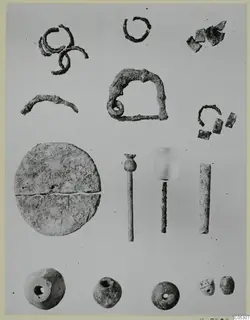 Corroded metal rings, fragments and pins, a disc and four beads laid out on a grey background, from Lapithos Tomb 403
