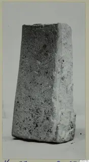 Tapered stone block from Kythrea, standing alone on a pale surface against a plain background