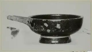 Black-glazed bowl with a long horizontal handle and a ring foot, seen from the side, from Marion tombs 31–45 finds