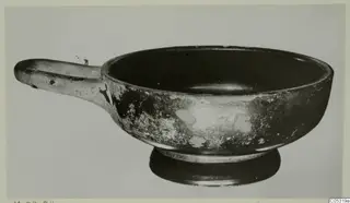 Black glazed bowl with a long horizontal handle and a low ring foot, from Marion