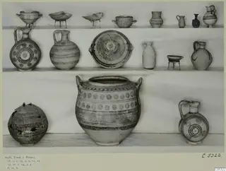 Group of pottery vessels from Stylli, Tomb 2, arranged on shelves against a plain backdrop