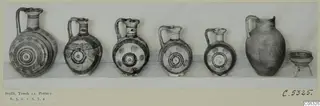 Seven vessels from Tomb 12 at Stylli: five painted jugs with circle motifs, a plain large jug and a small footed bowl.