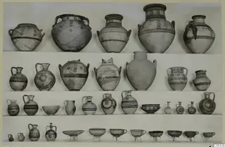 Four rows of painted pottery jars, jugs and bowls displayed on shelves, from Marion Tomb 10