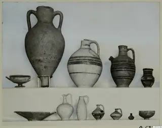 Pottery vessels from Marion Tomb 26: an amphora, jugs, a bowl and a dish, set out on two shelves.