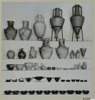 Rows of pottery vessels from Marion, Tomb 34: jars, jugs, bowls and small dishes against a pale background.