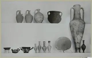 Pottery from Tomb 66 at Marion: jugs, a two-handled jar, a tall two-handled jar and small bottles on two shelves