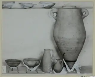 Pots and bowls from Tomb 35 at Marion, set out on a shelf against a plain pale background.