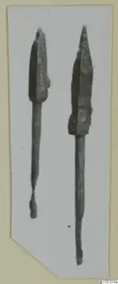 Two metal weapons with pointed blades and long tangs, shown side by side on a pale card