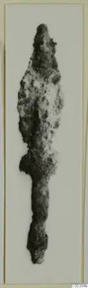 Corroded iron spearhead with a pointed blade and long tang, shown alone against a white background.