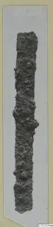 Long, narrow corroded iron object from Marion, photographed upright on a card mount.