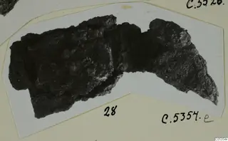 Corroded iron object from Marion, shown on a white card mount with handwritten number labels