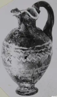 Sand-core glass jug with a tall curved handle and white wavy trails on its body